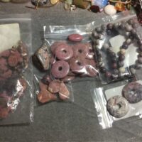 An array of jewelry-making supplies including gemstone donuts, beads, and stringing material.